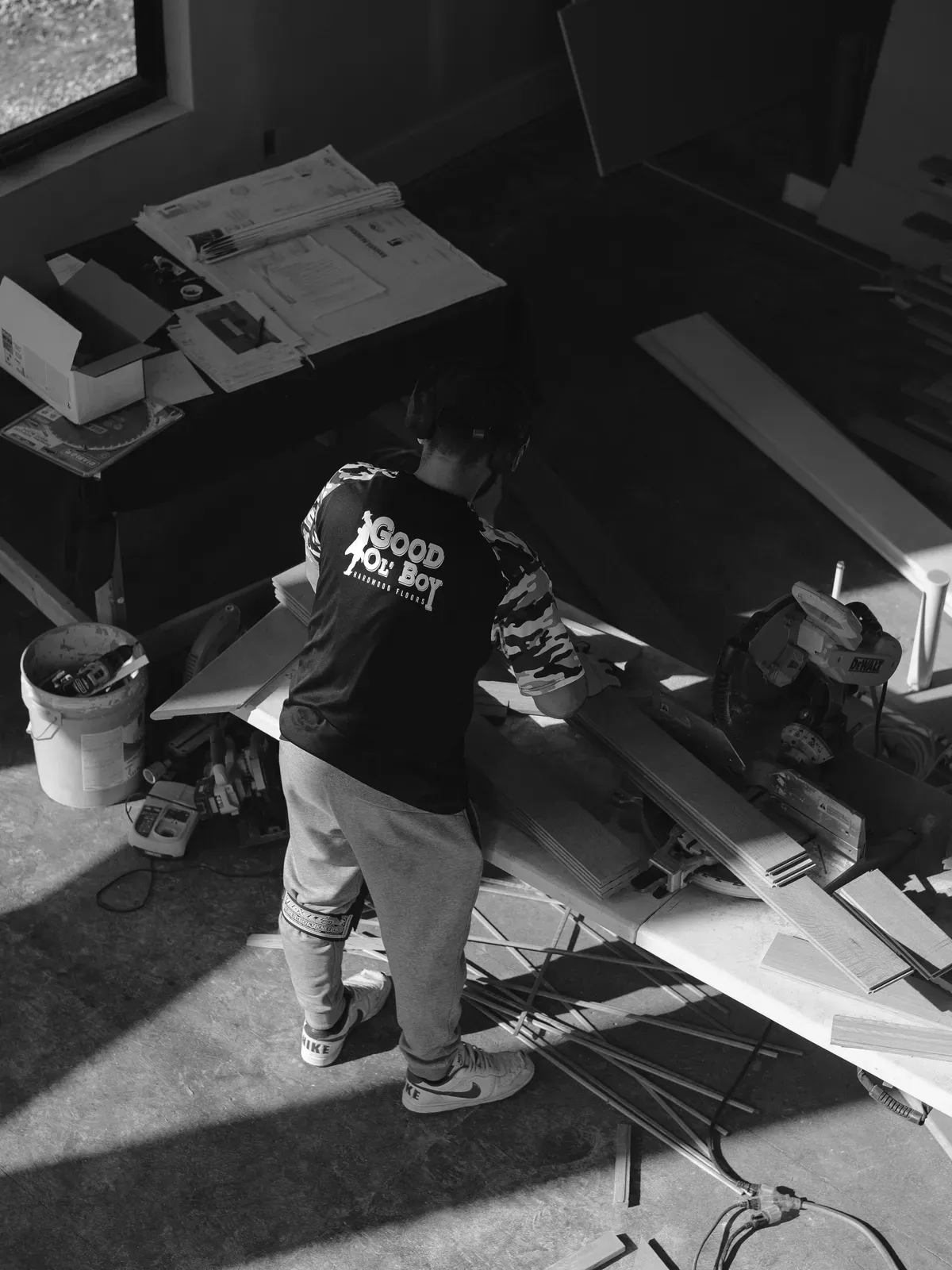 Good Ol' Boy Hardwood Floors crew member in a branded shirt cutting hardwood on a Kansas City job